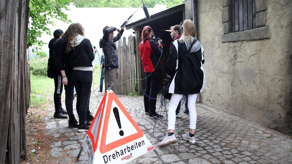 Filmcrew mit Kamera und Ton-Angel aus Schülern auf einem Weg im Filmpark Babelsberg